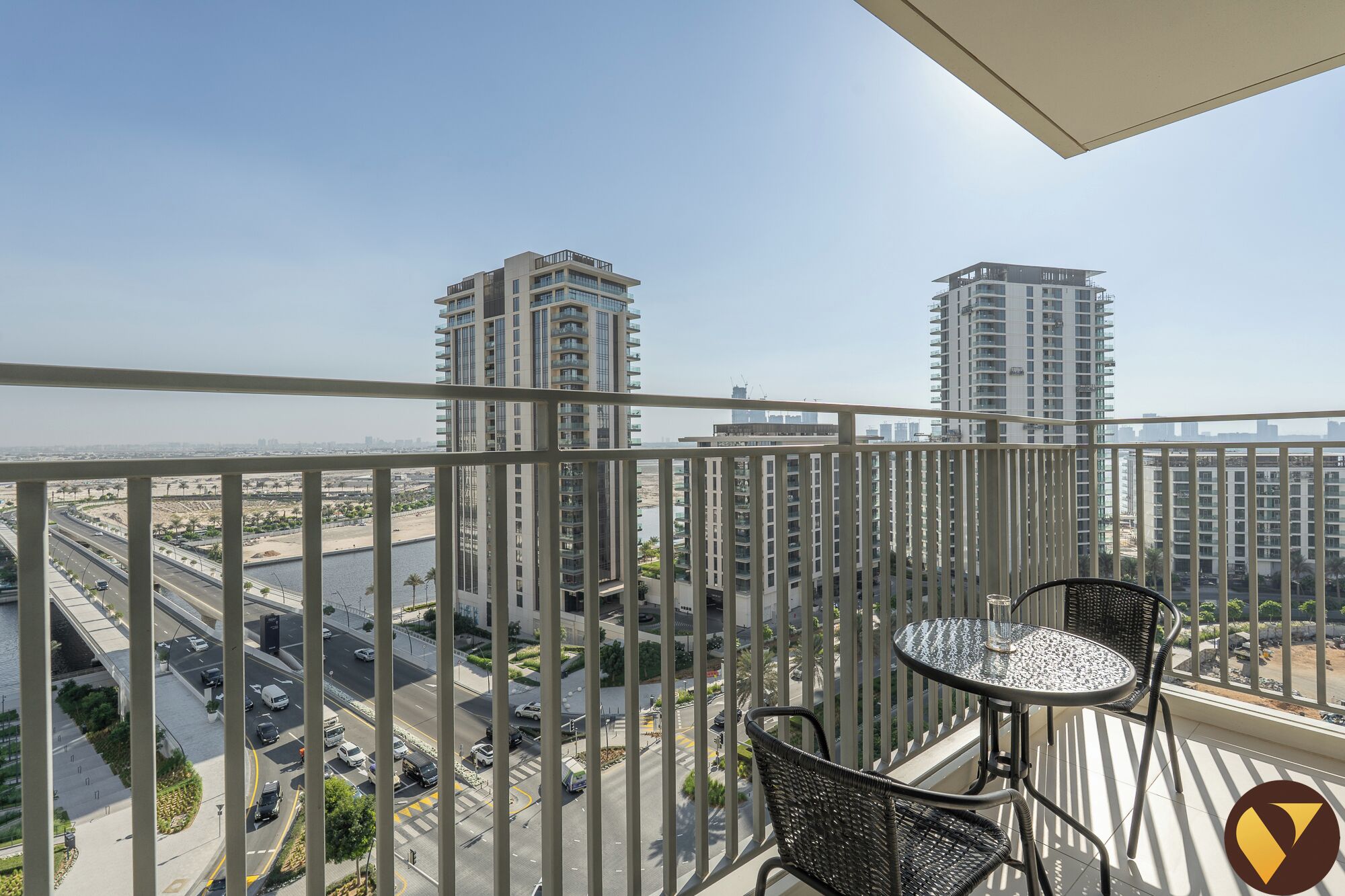 A balcony with a view of a cityscape, featuring high-rise buildings and a river.