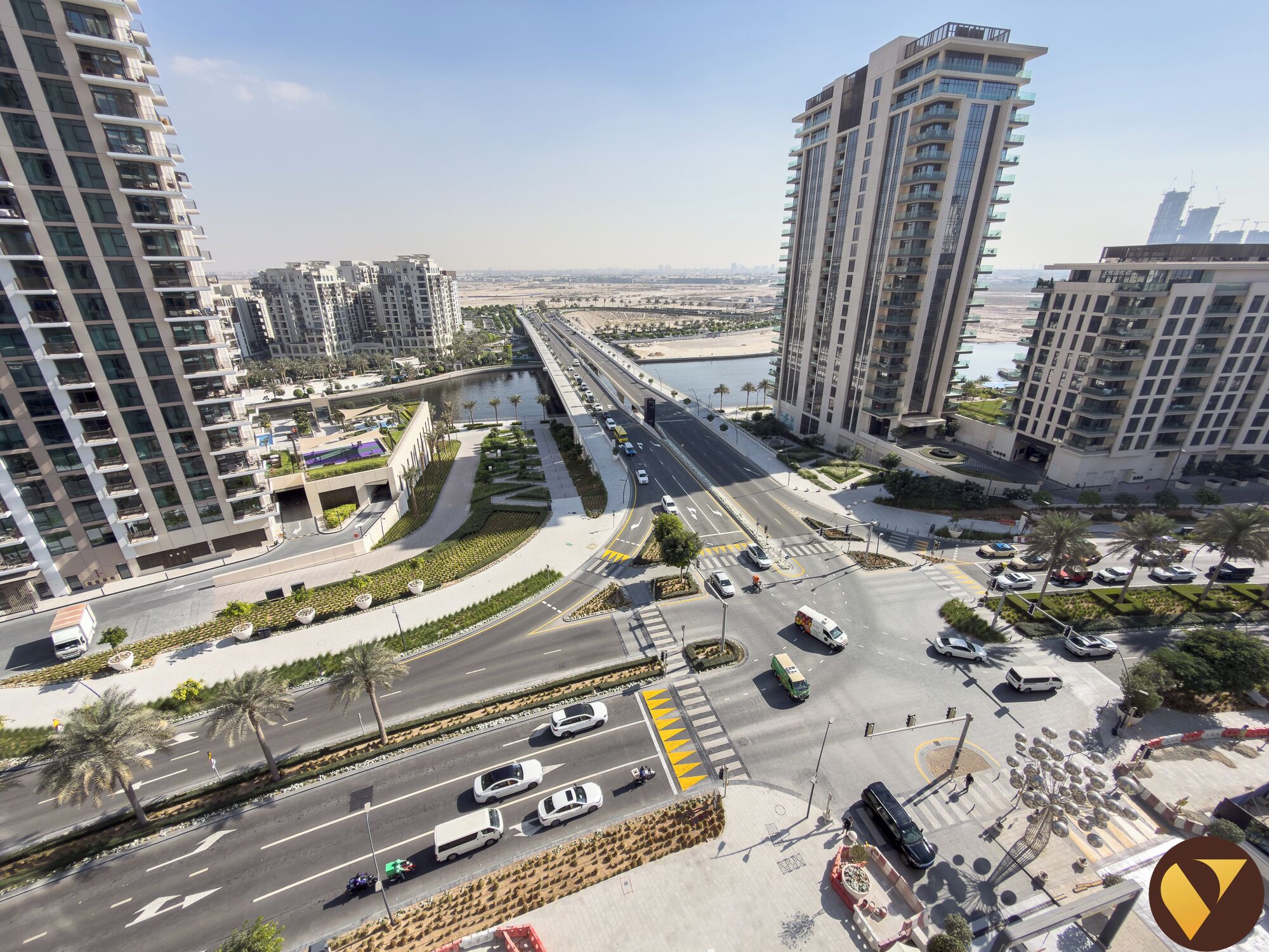A high-rise building with multiple floors, a road with vehicles, and a body of water in the background.