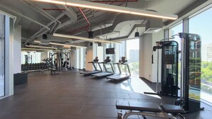 Een moderne sportschool met loopbanden, krachttoestellen en een groot raam met uitzicht op de stad.