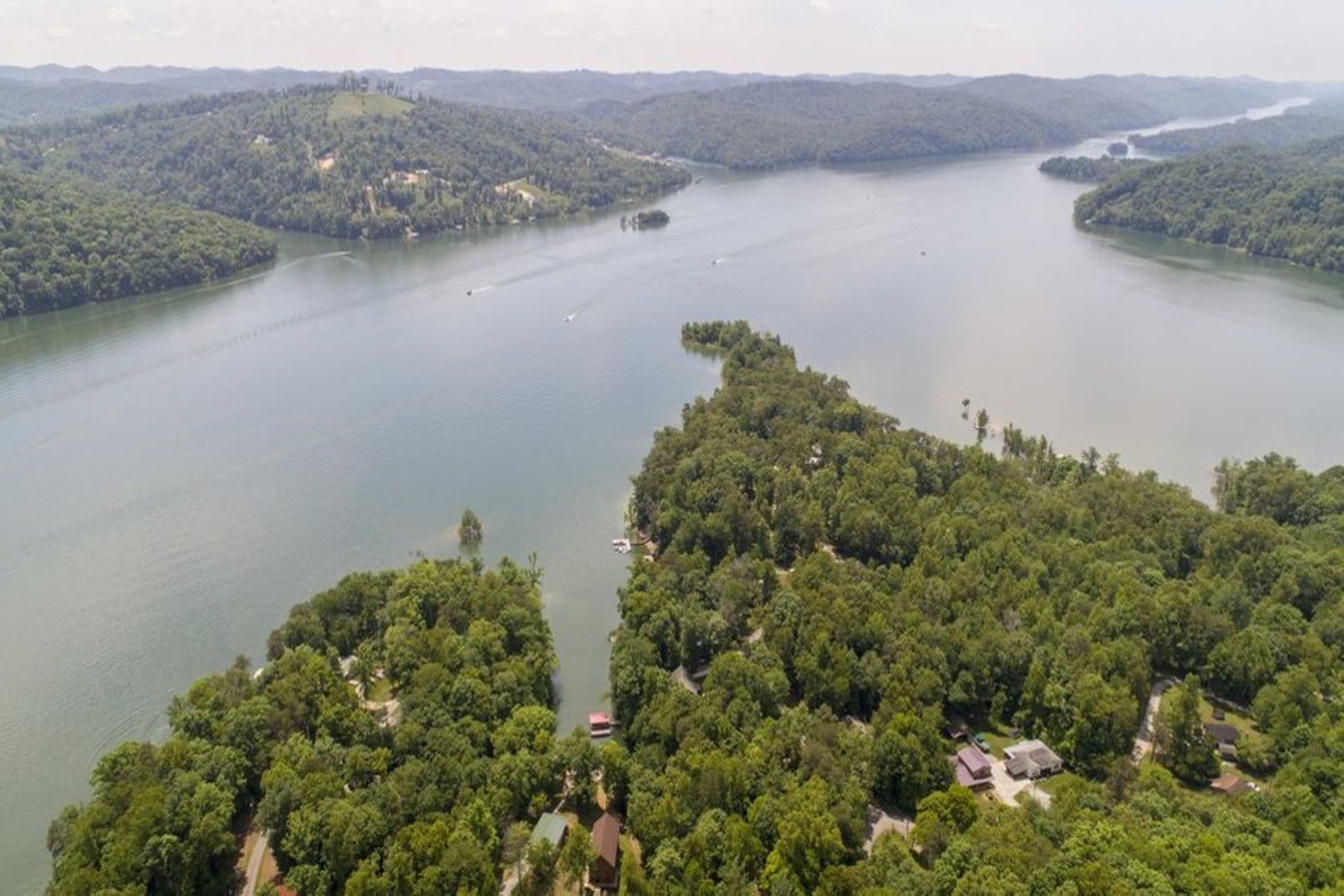 An aerial view of a lake surrounded by dense forest and hills.