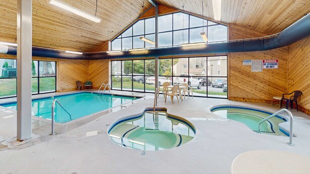 Una piscina interna con due zone distinte, pareti in legno e ampie finestre.