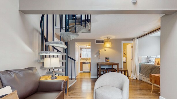 Un salon moderne avec un escalier, un canapé, un fauteuil et un coin repas.