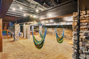 Une pièce avec un mur en pierre, un hamac et un escalier en bois.