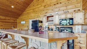 Ein Holzblockhaus-Interieur mit Barbereich, Küche und Sitzgelegenheiten.