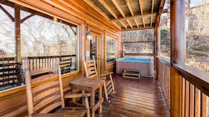 A wooden deck with a hot tub, wooden chairs, and a table. - Mtn Retreat, for 12・Hot Tub・Games・Deck・Shared Pool (Sevierville)