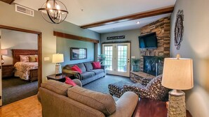 A spacious living room with a large sofa, a coffee table, and a fireplace. There is a television mounted on the wall and a sign above the fireplace that reads "Welcome to the Residence." - Charming Dollywood Retreat・Hot Tub & Pool Access (Sevierville)
