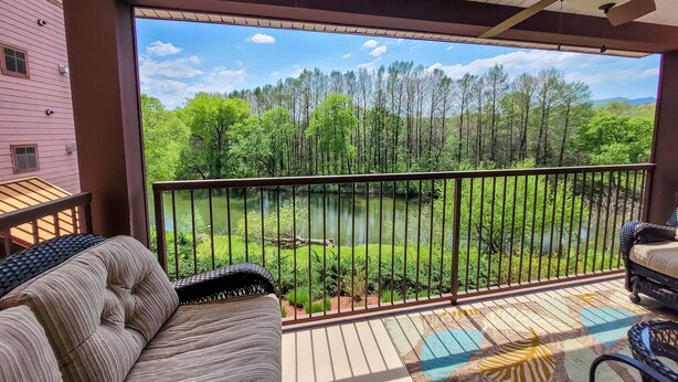 A balcony with a view of a lake, surrounded by trees and a wooden deck. - Charming Dollywood Retreat・Hot Tub & Pool Access (Sevierville)