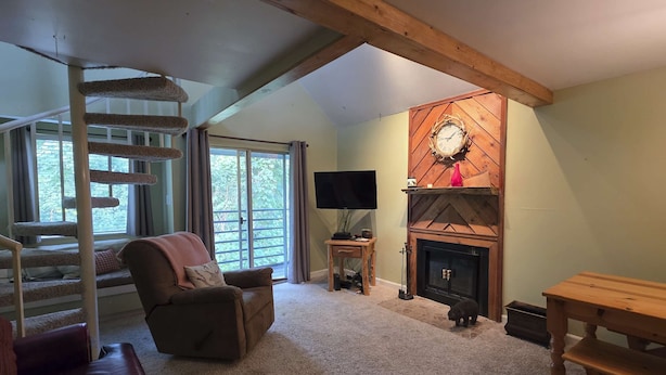 A cozy living room with a fireplace, a cat tree, a comfortable sofa, and a television. - Gatlinburg Condo, for 6・Pools・Hot Tub・Lovely Views (Gatlinburg)