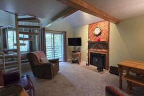 A cozy living room with a fireplace, a cat tree, a comfortable sofa, and a television. - Ski Mountain Condo | Stunning Views & Balcony (Gatlinburg)