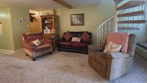 A cozy living room with a patterned armchair, a red leather sofa, and a brown recliner. A wooden cabinet and a framed picture adorn the walls. - Gatlinburg Condo, for 6・Pools・Hot Tub・Lovely Views (Gatlinburg)