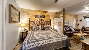 Una habitación acogedora con una cama, cabecera de madera, sofá de cuero y una mesa de centro de madera.