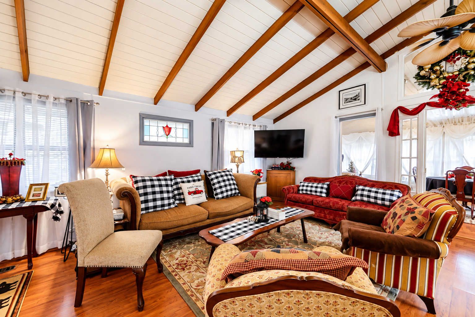 Una sala de estar acogedora con techo alto, vigas de madera, chimenea y televisor.
