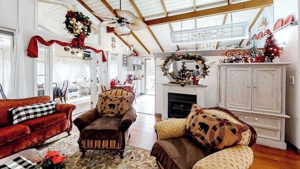 Un salón amplio con techo alto, chimenea y un árbol de Navidad.