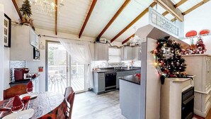 Una cocina moderna con una isla central, un comedor con una mesa preparada para dos personas y un árbol de Navidad.