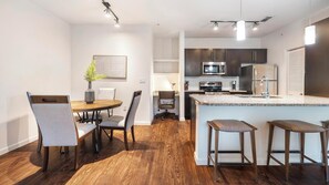 Una cocina moderna con armarios oscuros, un refrigerador de acero inoxidable y un microondas.