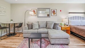 A modern living room with a sectional sofa, a small round table, and a single bed. - Relaxing Studio, Sleeps 2, Near Golf & Douglas Lake (Baneberry)