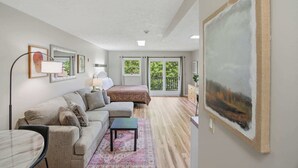 A modern bedroom with a large bed, a sofa, a small table, and a painting on the wall. - Relaxing Studio, Sleeps 2, Near Golf & Douglas Lake (Baneberry)