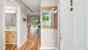 A hallway with wooden flooring, a white door with a number, and a view of a backyard through a glass door. - Relaxing Studio, Sleeps 2, Near Golf & Douglas Lake (Baneberry)