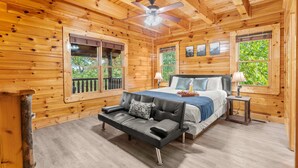 Ein Schlafzimmer einer Holzhütte mit einem Bett, einem Sofa und einem Deckenventilator.