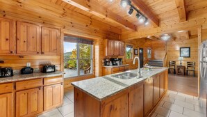 Ein Interieur einer Holzhütte mit einer Küche, die sich durch Granitarbeitsplatten, Holzschränke und eine zentrale Kochinsel mit Spüle auszeichnet.