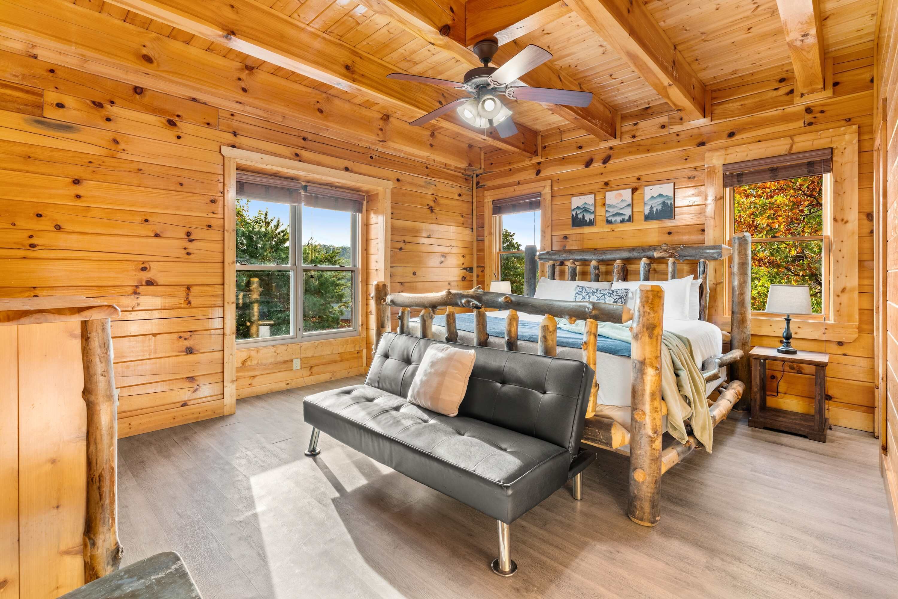 Ein Schlafzimmer in einer Blockhütte mit einem Bett, einem Sofa und einem Deckenventilator.