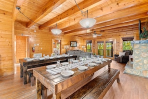 A spacious wooden cabin with a large dining table set for six, a stone fireplace, and a cozy seating area. - Large Cabin Sleeps 58 | Views | Theater | 2 Hot Tubs (Sevierville)