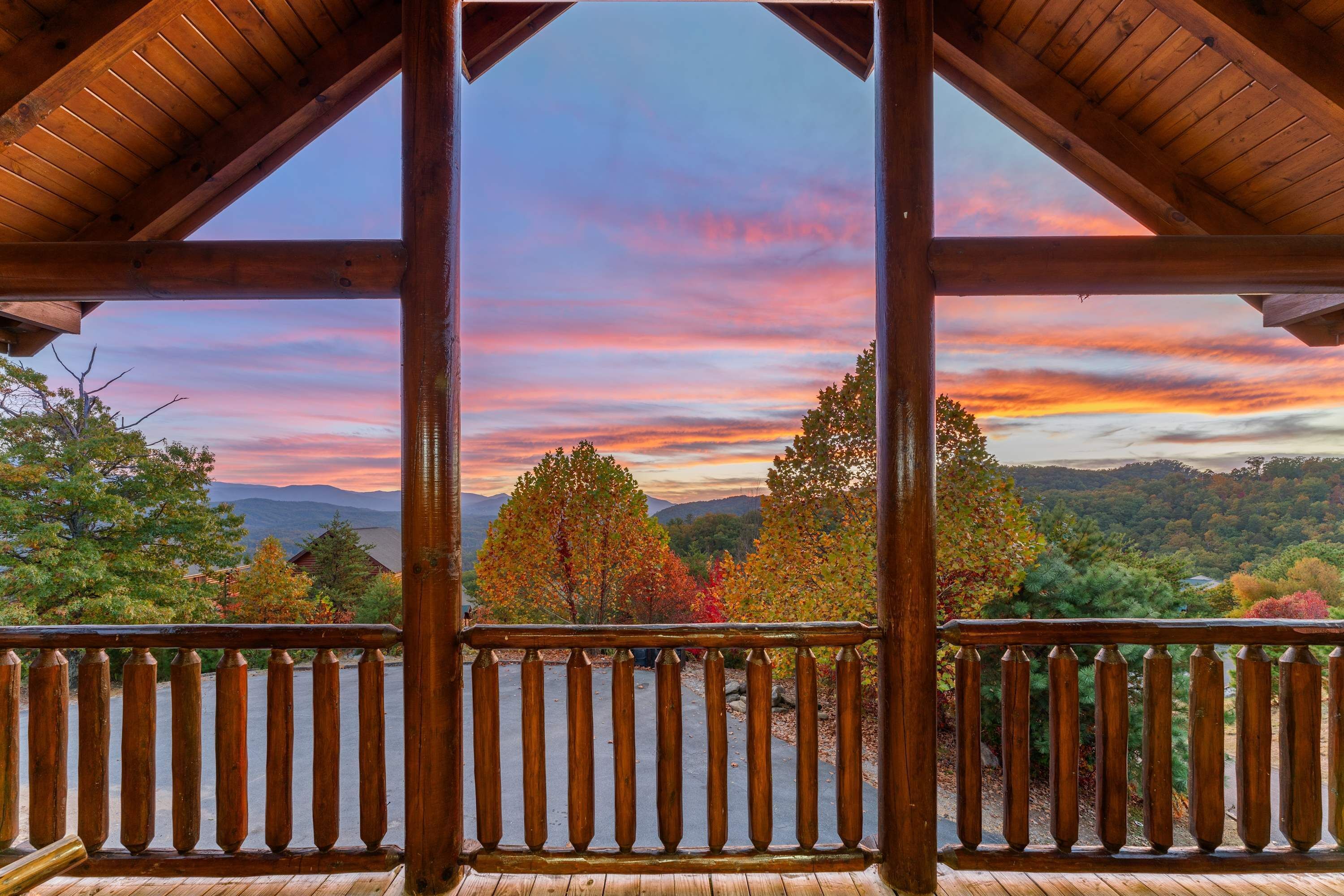 Eine Holzterrasse mit Blick auf Herbstlaub und Berge.