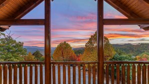 Eine Holzterrasse mit Blick auf Herbstlaub und Berge.