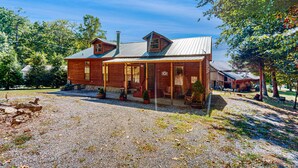 Een houten chalet met een veranda, schoorsteen en een grindpad.