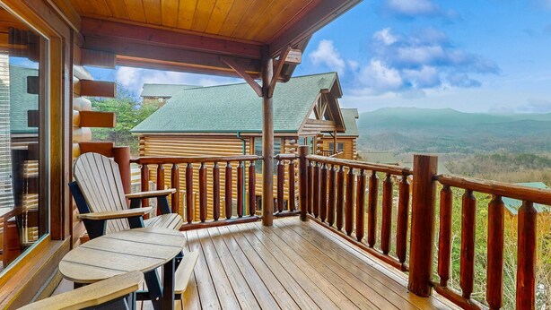 A wooden deck with Adirondack chairs and a table, overlooking a mountainous landscape. - Lovely Cabin, Sleep 6・Hot Tub・Mtn View・Pool Access (Sevierville)