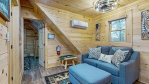 A cozy cabin interior with a blue sofa, a small wooden table, and a fire extinguisher. - Mountain Cabin Retreat・Hot Tub・Arcade・Fireplace (Sevierville)