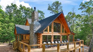 A log cabin with a stone chimney, wooden deck, and outdoor seating area. - Mountain Cabin Retreat・Hot Tub・Arcade・Fireplace (Sevierville)