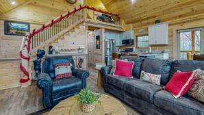 A cozy cabin interior with a staircase, leather sofas, a dining area, and a kitchen. - Mountain Cabin Retreat・Hot Tub・Arcade・Fireplace (Sevierville)