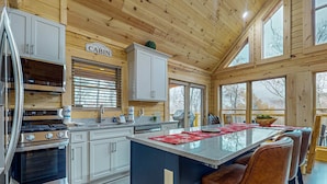 A modern kitchen with a central island, bar stools, and a 'Welcome Cabin' sign. - Mountain Cabin Retreat・Hot Tub・Arcade・Fireplace (Sevierville)