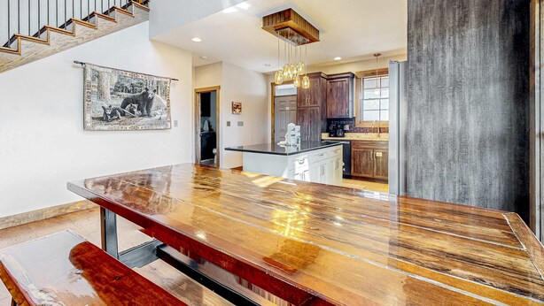 Een ruime keuken met moderne apparatuur, een houten eettafel en een trap naar een hoger niveau.