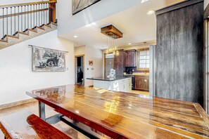 A spacious kitchen with modern appliances, a wooden dining table, and a staircase leading to an upper level. - 5BR Gatlinburg Cabin | Views • Hot Tub • Game Room (Gatlinburg)