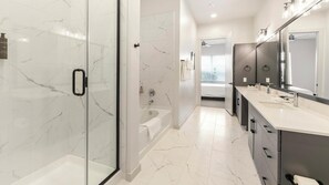 Uma casa de banho moderna com chuveiro envidraçado, banheira e toucador com um espelho grande.