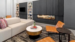 A modern living room with a sofa, a coffee table, and a fireplace. - Landing | Incredible 2BD, Gym, Pool (Plano)