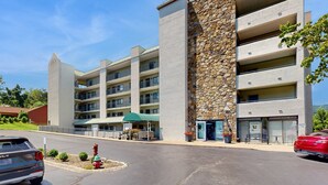 Ein mehrstöckiges Hotel mit Steinfassade, Balkonen und einem Parkplatz.
