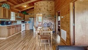 A spacious kitchen with wooden cabinets, a dining area with a wooden table and chairs, and a high ceiling with exposed beams. - Secluded Smoky Mtn Cabin Escape・Views・Pet Friendly (Townsend)