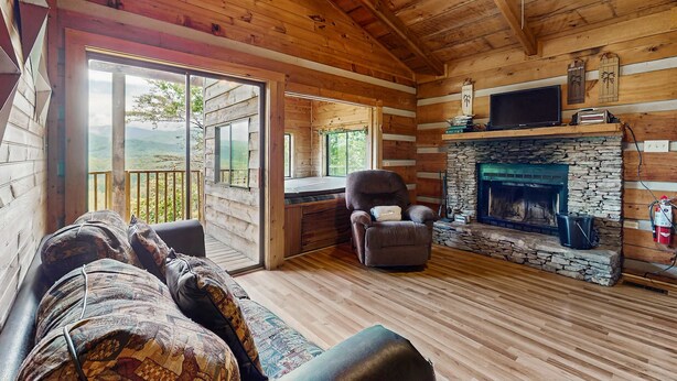 A log cabin interior with a stone fireplace, a sofa, a recliner, and a television. - Secluded Smoky Mtn Cabin Escape・Views・Pet Friendly (Townsend)
