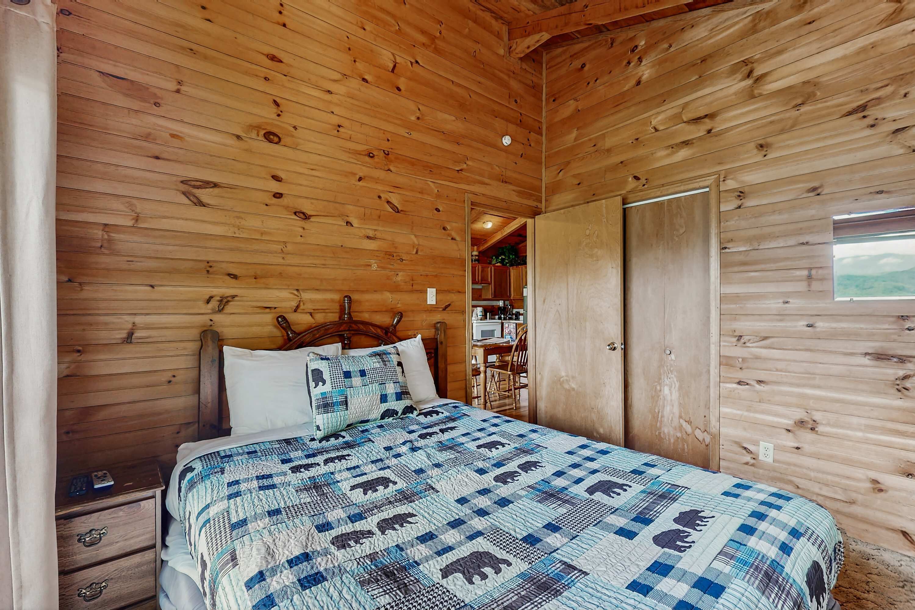Un dormitorio con paneles de madera, una cama, una mesita de noche y vistas a la cocina.