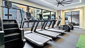 A modern gym with treadmills, exercise bikes, and a ceiling fan. - Landing | Spectacular 2BD, Pool, Gym (Plano)