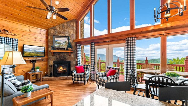 A cozy cabin interior with a fireplace, wooden walls, a balcony with a scenic view, and a dining area. - Bearfoot Inn, Sleeps 6・Stunning Views・Games (Sevierville)