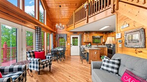 A cabin interior with a dining area, a living room with a sofa, and a kitchen. - Bearfoot Inn, Sleeps 6・Stunning Views・Games (Sevierville)