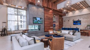A spacious living area with a large TV, comfortable seating, and a modern kitchen area. - Landing | Stunning 1BD, Gym (San Antonio)