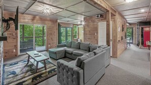 L’intérieur d’une cabane en rondins, avec un canapé d’angle, une petite table et un lustre.