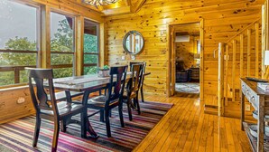 Un intérieur en bois avec une table et des chaises, de grandes fenêtres et un escalier.