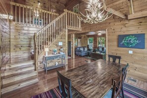 A wooden interior with a staircase, a dining area, and a living room. - Cozy Mtn View Home, Sleeps 15, Hot Tub, Games, Gym (Sevierville)