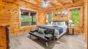 A wooden cabin bedroom with a bed, a sofa, and a small table. - Sleeps 116 | Smoky Mountain Views | 4 Hot Tubs | 2 Game Rooms | (Sevierville)